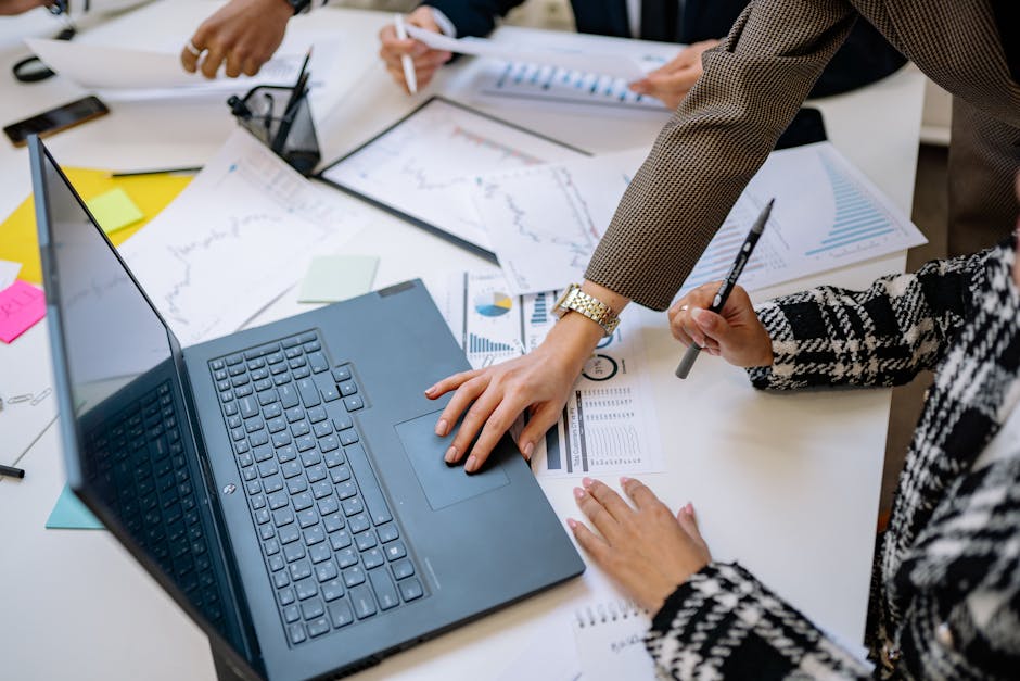 Business team analyzing data and charts during a meeting with a laptop on the table.